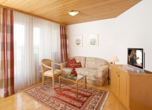 a living room with a couch and a tv at Hotel Rose in Bretzfeld