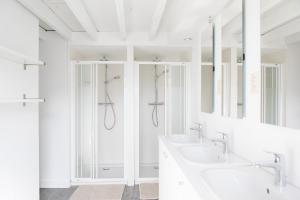 La salle de bains blanche est pourvue de deux lavabos et de miroirs. dans l'établissement Villa Wellington, à Ostende