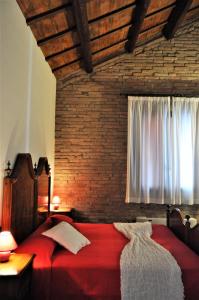 a bedroom with a red bed with a brick wall at Corte Dossello in Migliaro +58 photos