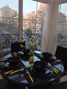 a table with plates and utensils on top of a balcony at Luxury Mohandeseen Apartment in Cairo