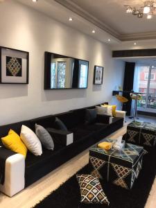 ein Wohnzimmer mit einem schwarzen Sofa und gelben Kissen in der Unterkunft Luxury Mohandeseen Apartment in Kairo