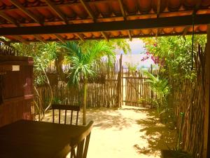 a patio with a table and a fence and palm trees at Casa Bougainvilla in Jericoacoara