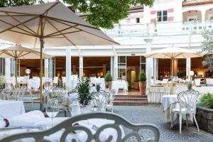 un restaurant avec des tables blanches, des chaises et des parasols dans l'établissement Romantik Hotel Oberwirt, à Marlengo