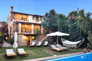 a house with a swimming pool and chairs and an umbrella at Villa Arhontariki in Kissamos