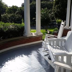 twee witte stoelen op een veranda met zuilen bij Thomasville Bed and Breakfast in Thomasville