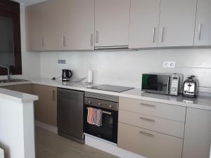 een keuken met witte kasten, een magnetron en een fornuis bij Luxury 3 bedroom apartment TH006 in Torre de la Horadada