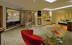 a living room with a red chair and a bed at Iakovakis Suites & Spa in Koropi