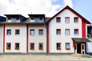 biały dom z czerwoną ozdobą i oknami w obiekcie Hotel Zum Stern Spreewald w mieście Werben