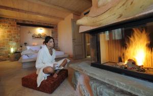 a woman sitting in a room with a fireplace at Iakovakis Suites & Spa in Koropi