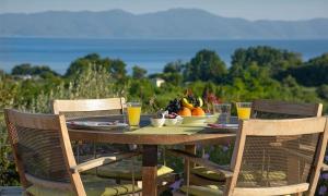 a wooden table with a bowl of fruit and glasses of orange juice at Iakovakis Suites & Spa in Koropi