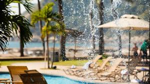 a fountain in a swimming pool with people laying on chairs at Pierre Mundo Imperial Riviera Diamante Acapulco in Acapulco