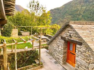 um pequeno edifício de pedra com uma porta vermelha numa montanha em Rustici Maggia em Aurigeno