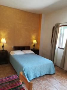 a bedroom with a bed with a blue blanket at Casa Jocotenango in Guatemala