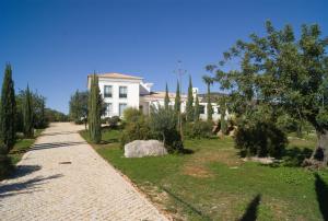 a white house with trees and a brick road at Quinta da Esteva in Moncarapacho