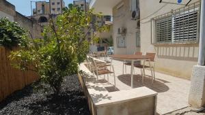 un patio con mesa, sillas y un árbol en Hili Apartments, en Tiberíades