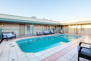 a swimming pool with patio furniture and chairs around it at Best Western Crystal Inn in Bendigo