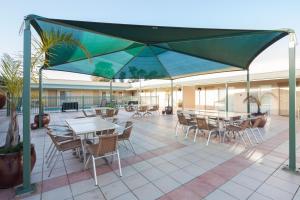 patio ze stołami i krzesłami oraz zielonym parasolem w obiekcie Best Western Crystal Inn w mieście Bendigo