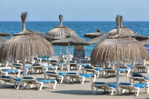 a bunch of chairs and umbrellas on a beach at Estepona Real Apartamentos in Estepona