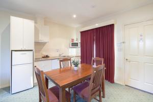 a kitchen with a wooden table and chairs and a kitchen with a refrigerator at Best Western Crystal Inn in Bendigo