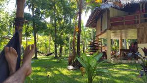 a person laying in a hammock in front of a house at Water to Forest Ecolodge in Loboc