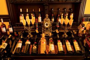 a bunch of wine bottles on a shelf with a clock at Iris Villa in Vatra Dornei