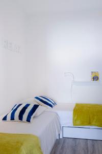 バレアルにあるSilver Coast - Casa da Ilhaの白いベッドルーム(黄色と青の枕付きのベッド2台付)