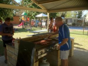 a man standing in front of a grill cooking food at Nagambie Caravan Park & Motel in Nagambie