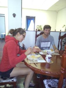 mężczyzna i kobieta siedzący przy stole jedzący jedzenie w obiekcie ANGIE`s HOUSE w mieście Manizales