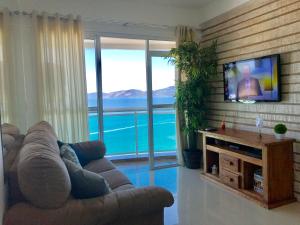 Il comprend un salon doté d'un canapé et d'une télévision à écran plat. dans l'établissement Porto Real Suites Apto Luxo com vista p/ Mar, à Mangaratiba