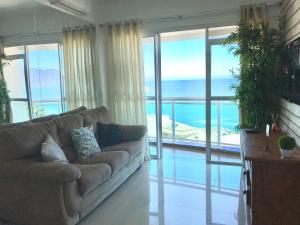 - un salon avec un canapé et une vue sur l'océan dans l'établissement Porto Real Suites Apto Luxo com vista p/ Mar, à Mangaratiba