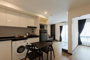 a kitchen with a washing machine and a table and chairs at Zensation The Residence Bangkok in Bangkok