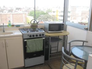 a kitchen with a stove and a microwave at Posada Peregrinus in Lima