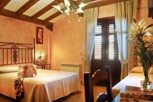a bedroom with two beds and a table and a ceiling at Hospedería Ruta de Lorca in Alfacar