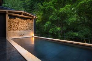 a house with a swimming pool and a wood wall at Tateshina Shinyu Onsen in Chino