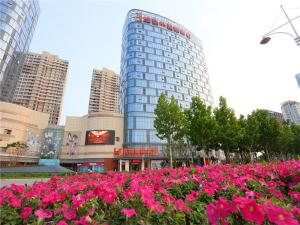 a bunch of pink flowers in front of a building at Vienna International Hotel Yantai Changjiang Road Xingyi Square Branch in Yantai