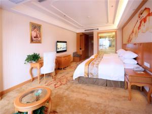 una camera d'albergo con un grande letto e una scrivania di Vienna International Hotel Yantai Changjiang Road Xingyi Square Branch a Yantai