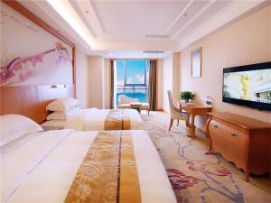 um quarto de hotel com duas camas e uma televisão de ecrã plano em Vienna International Hotel Yantai Changjiang Road Xingyi Square Branch em Yantai