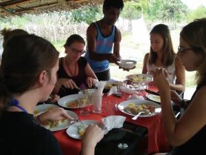 Pasikudah Eco Village Hotel في باسيكودا: مجموعة من الناس يجلسون حول طاولة يأكلون الطعام