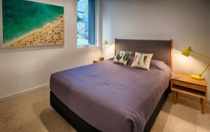 a bedroom with a bed and a picture of a beach at Orange Stay Townhouses in Melbourne