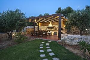 a pergola with a picnic table in a yard at Olive Garden Villas in Perama