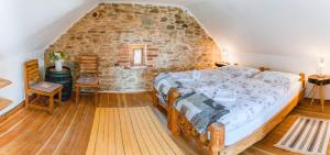 1 dormitorio con 1 cama grande y pared de piedra en Osada Havranů en Hnanice