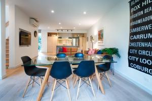 a dining room with a glass table and blue chairs at Orange Stay Townhouses in Melbourne
