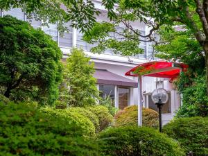 a red umbrella in front of a house with bushes at TKP Lectore Hakone Gora in Hakone