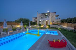 a swimming pool in front of a house at Olive Garden Villas in Perama
