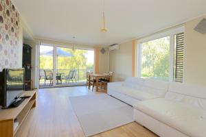 een woonkamer met een witte bank en een televisie bij Papli 34 Apartment with pool in Pärnu