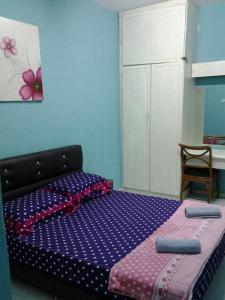 Un dormitorio con una cama con sábanas moradas y una silla en Adiana Homestay, en Kuah