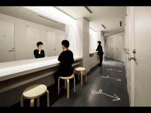 東京にあるナインアワーズウーマン神田の脱衣所のカウンターに座る女