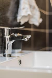 un rubinetto cromato su un lavandino del bagno di SweetHome Dijon - Black & White a Digione Altre 48 foto