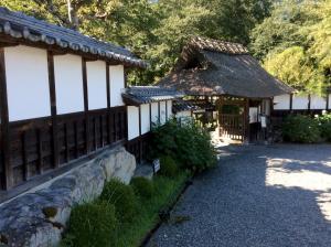 a house with a thatched roof and a stone wall at Jonni`s Place in Sakamoto