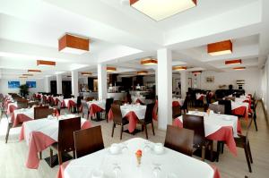 un restaurante con mesas y sillas blancas y servilletas rojas en Evenia President, en Salou